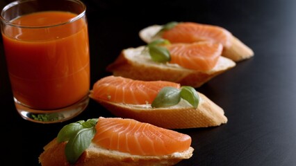 Salmon topped with cheese and basil delivers indulgent flavors in every bite. Paired with orange-carrot juice, this eco-conscious meal combines richness and freshness for health-focused enjoyment.