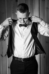 Elegant Preparation: A Man Adjusting His Suit Jacket in Classic Black and White