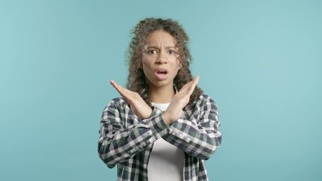 No, never, pretty african american teen girl disliking and rejecting gesture by stop crossing hands sign. Cute woman disapproving sign make negation sign on blue studio background. Ban, timeout.