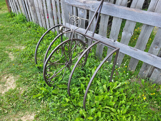 Forged bike rack near a wooden fence on the green grass.