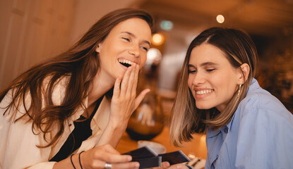 Photo of good looking young women in summer clothing, spend spare time together, watch photo card, nostalgia rest in restaurant. Two girls sisters laughing, have a good time.