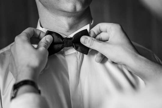 Elegant Preparations: Hands Perfectly Adjusting a Classic Bow Tie in Black and White - Powered by Adobe