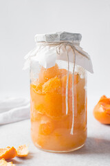 tangerine cheong in a glass jar on a white background, korean tangerine cheong in a transparent jar, tangerine in sugar syrup, process of making tangerine cheong