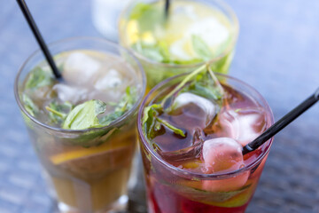 Three drinks with ice and straws in glasses