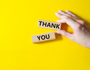 Thank you symbol. Wooden blocks with words Thank you. Businessman hand. Beautiful yellow background. Business and Thank you concept. Copy space.