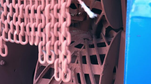 Metal chain before moving parts of wood debarking industrial machine on factory. Conveyor line in timber manufacturing. Engineering technology in production. Modern equipment for woodworking industry.