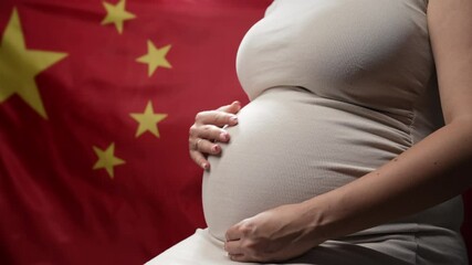Unrecognizable future mother expecting baby on chinese national flag background. Pregnant woman touching belly. Demography crisis, population problems in China.