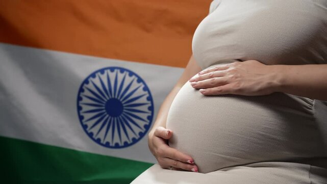 Unrecognizable future mother expecting baby on indian national flag background. Pregnant woman touching belly. Demography, population in India