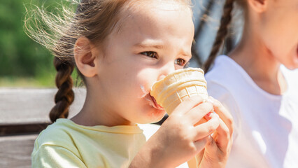 little girl eating ice cream in the summer in the park. cheerful girl with ice cream.