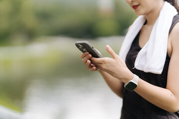 Fitness Focus: Young woman in sportswear checks fitness tracker app on smartphone during outdoor workout, showcasing technology integration in active lifestyle