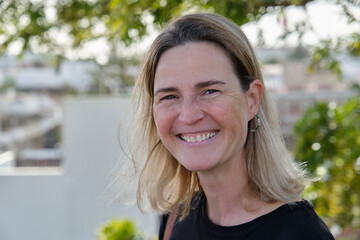 A mature smiling woman standing smiling in the garden in summertime