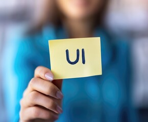 Person holding a note with the text UI for user interface.