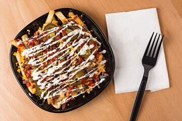 Special Loaded Fries with Cheese, Bacon, Jalapenos, and Sauces served in plate isolated on wooden table top view fast food snacks