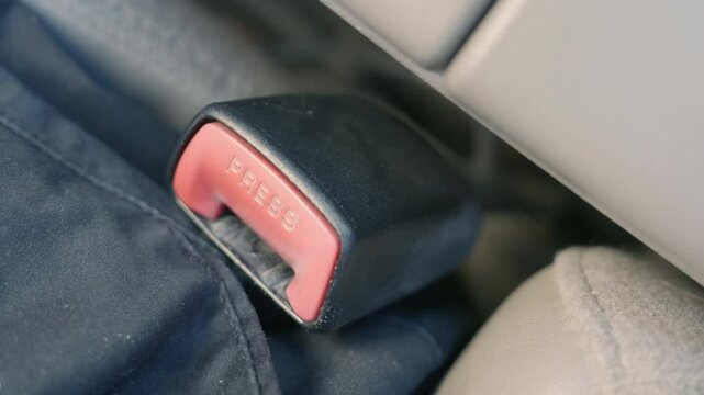 Seatbelt Unbuckling Close-up: Hand Releasing Car Safety Latch. Vehicle Exit Mechanism in Action. Automobile Journey Completion. Driver Departure Closeup