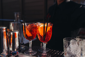 Bartender working, beautiful row line of different coloured liquor alcohol cocktails on a open air party in a bar, and others on catering banquet on event, barman mixing drinks and beverages in club