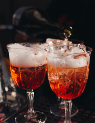Bartender working, beautiful row line of different coloured liquor alcohol cocktails on a open air party in a bar, and others on catering banquet on event, barman mixing drinks and beverages in club
