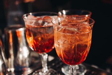 Bartender working, beautiful row line of different coloured liquor alcohol cocktails on a open air party in a bar, and others on catering banquet on event, barman mixing drinks and beverages in club