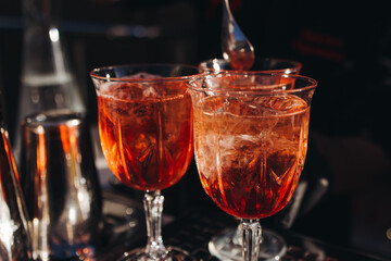 Bartender working, beautiful row line of different coloured liquor alcohol cocktails on a open air party in a bar, and others on catering banquet on event, barman mixing drinks and beverages in club