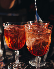 Bartender working, beautiful row line of different coloured liquor alcohol cocktails on a open air party in a bar, and others on catering banquet on event, barman mixing drinks and beverages in club