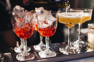 Bartender working, beautiful row line of different coloured liquor alcohol cocktails on a open air party in a bar, and others on catering banquet on event, barman mixing drinks and beverages in club