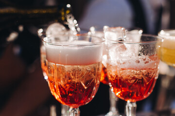 Bartender working, beautiful row line of different coloured liquor alcohol cocktails on a open air party in a bar, and others on catering banquet on event, barman mixing drinks and beverages in club