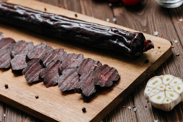 Sliced dark cured sausage on board, highlighting deep color and rich texture for gourmet appeal