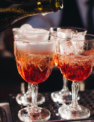 Bartender working, beautiful row line of different coloured liquor alcohol cocktails on a open air party in a bar, and others on catering banquet on event, barman mixing drinks and beverages in club