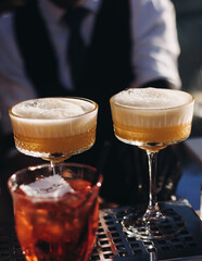 Bartender working, beautiful row line of different coloured liquor alcohol cocktails on a open air party in a bar, and others on catering banquet on event, barman mixing drinks and beverages in club