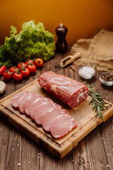 Fresh raw pork loin with rosemary on a wooden cutting board, perfect for cooking or grilling recipes