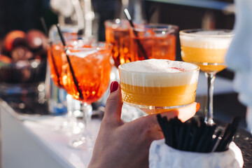Bartender working, beautiful row line of different coloured liquor alcohol cocktails on a open air party in a bar, and others on catering banquet on event, barman mixing drinks and beverages in club