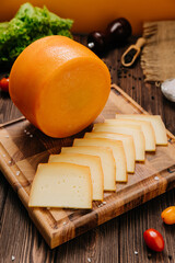 Wheel and slice of cheese on cutting board, perfect for culinary displays and gourmet presentations