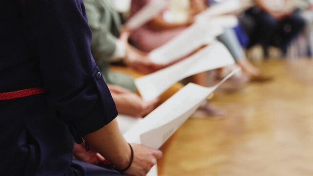 Choir rehearsal, vocal class singing in the auditorium hall, group of students on stage holding white sheets and singing, orchestra vocals class in music school with a teacher, adults sing in chorus