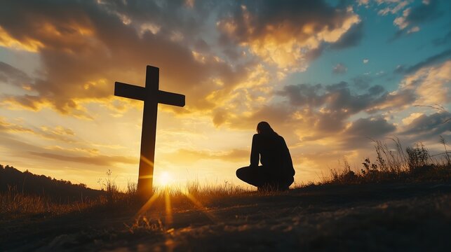 Silhouette of man kneeling near the wooden Christian cross on a nature meadow grass field outdoor at sunset. Religion faith belief repentance prayer, forgiveness hope in Jesus Christ, salvation