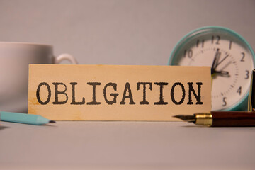 wooden block on table clock. text Obligations.
