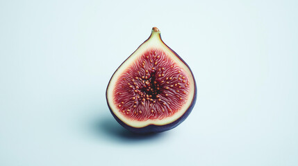 a single fig cut in half showing its deep purple skin and rich red interior with seeds against an isolated white background