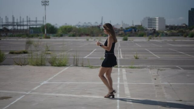 young girl caucasian woman in black dress short girl walking in profile to camera takes out small earphones from their case and puts them in her ears