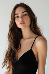 Fototapeta premium portrait of a woman with long brown hair, wearing a black dress, against a white background