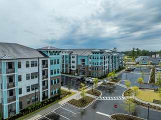 Aerial view of modern American apartment condo complex with turquoise vinyl siding dramatic colorful sunset sky after the rain