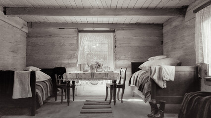 A historic rural room interior with wooden beds and a table covered in a lace tablecloth. Soft...