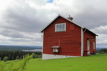 Obraz premium Summer day in August with clouds. Red house. Distance landscape nature photo. Jämtland, Sweden, Europe.