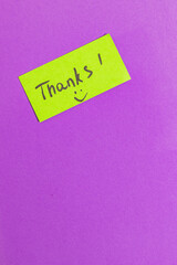 Green small note with the word thank you on purple background vertical photo