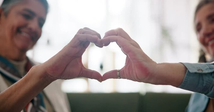 Mature lesbian couple, heart hands and love with bonding, smile and together in home as partner. Women, connection and happiness with affection, solidarity or support in living room as married people