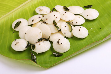 Many Idlis / idlyon plantain leaf in Kerala, India. made by steaming batter of fermented black lentils de-husked and rice.served with vegetarian side dish