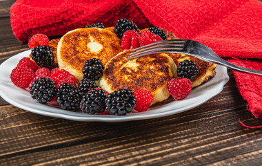Fresh cottage cheese pancakes with raspberry blackberry on a white plate