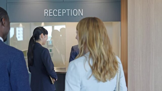 A group of multinational business people processing documents at a reception desk