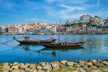 Obraz premium View of Porto city and Douro river with traditional boats with port wine barrels from famous tourist viewpoint Marginal de Gaia riverfront. Porto, Vila Nova de Gaia, Portugal