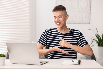 Young man using sign language during video call indoors