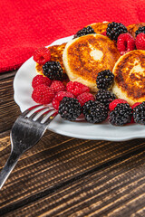Fresh cottage cheese pancakes with raspberry blackberry on a white plate