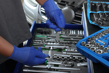 Auto mechanic with different tools at automobile repair shop, closeup