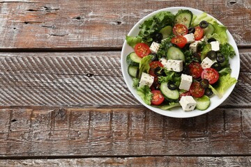Delicious salad with feta cheese on wooden table, top view. Space for text